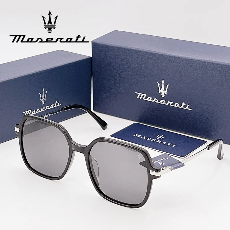 Kính râm màu đen hình vuông, hộp màu xanh đậm với logo và chữ "Maserati" màu trắng.