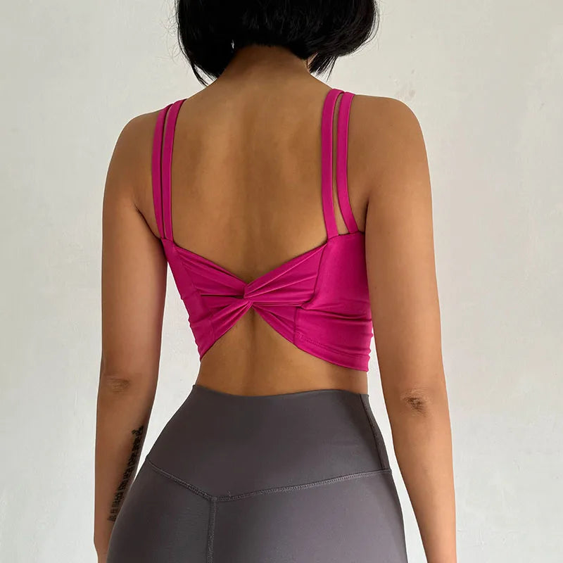Người mặc áo hồng hở lưng, quần legging xám, nền trắng.
