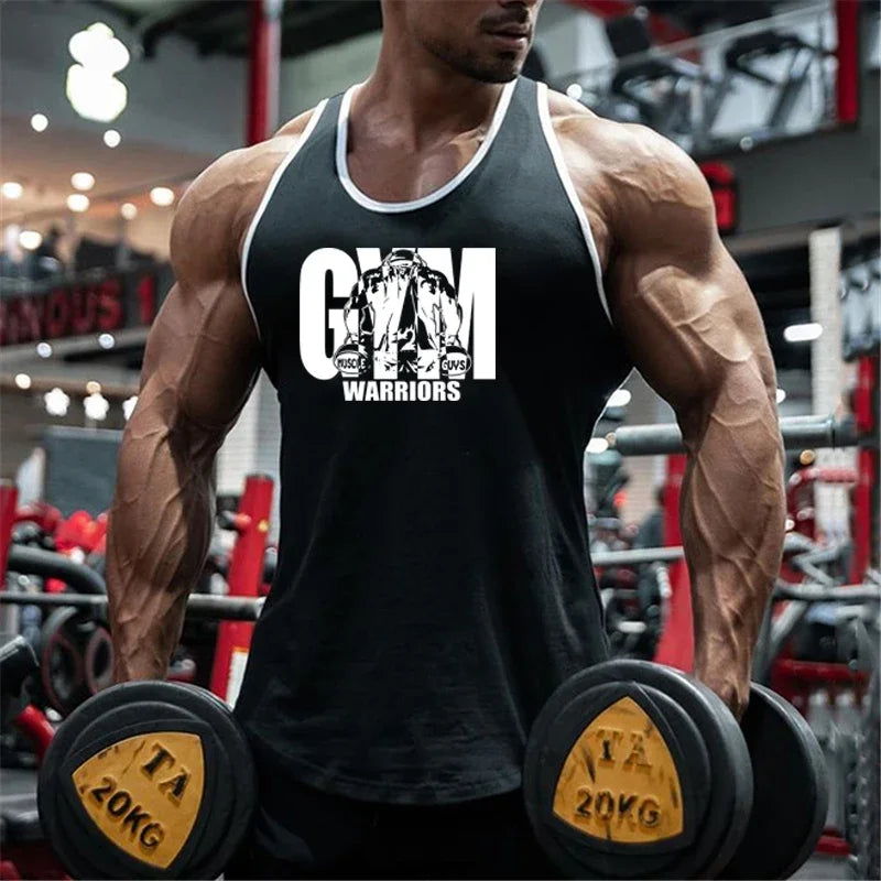 Người đàn ông mặc áo ba lỗ đen với chữ "GYM WARRIORS", cầm tạ 20kg trong phòng tập.