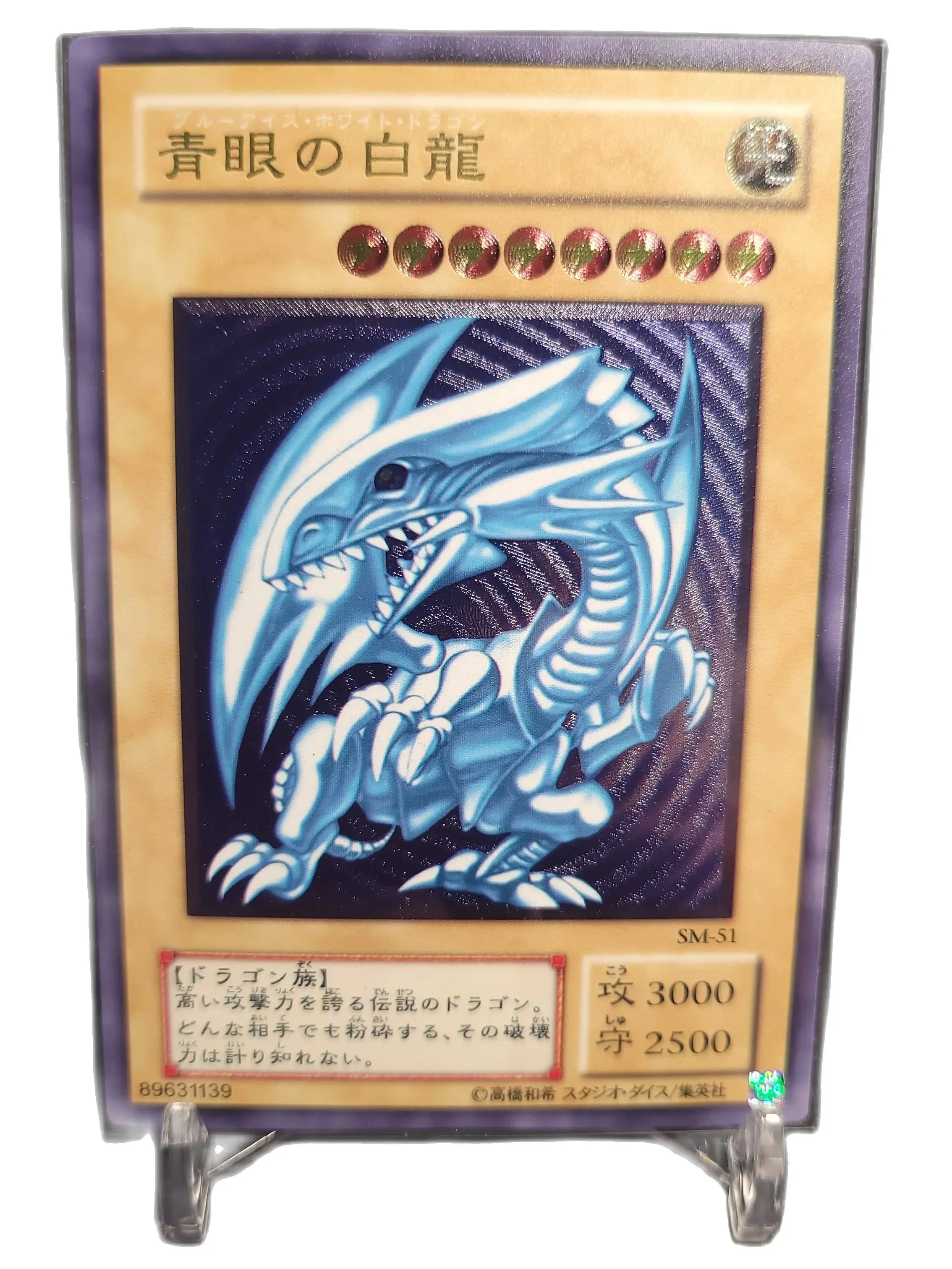 Thẻ bài với hình rồng xanh, viền vàng, có chữ Nhật Bản và biểu tượng tấn công/phòng thủ.