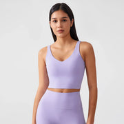 Người mẫu mặc áo crop top và quần tập màu tím nhạt, tóc đen dài, nền trắng.