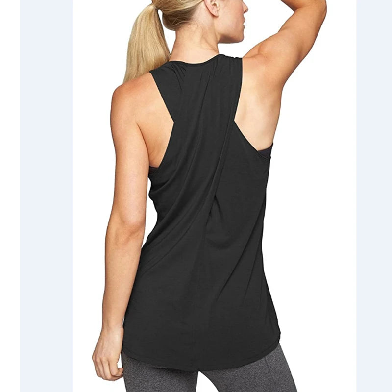 Người phụ nữ tóc vàng mặc áo tank top đen và quần legging xám, đứng quay lưng.
