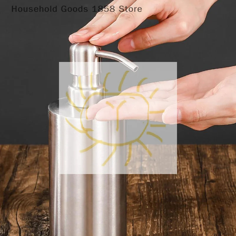Tay nhấn vào bình inox đựng xà phòng trên nền gỗ màu nâu.