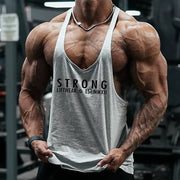 Người đàn ông cơ bắp mặc áo ba lỗ xám có chữ "STRONG" trong phòng tập gym.