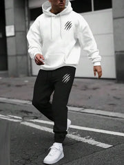 Người mặc áo hoodie trắng, quần đen có họa tiết trắng, đi giày thể thao trắng trên phố.