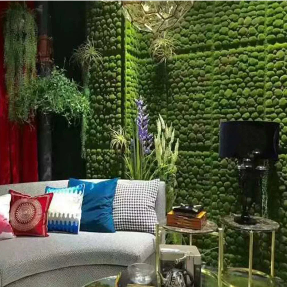 Ghế sofa với gối màu sắc sặc sỡ, tường rêu xanh, đèn bàn đen, cây xanh trang trí.
