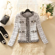 Áo khoác vải tweed trắng đen, túi nút, nằm trên thảm lông, cạnh hoa hồng và túi xách đen.