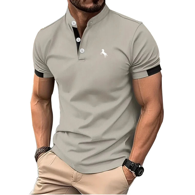 Người đàn ông mặc áo polo xám nhạt, cổ đứng, có logo trắng, tay áo đen.