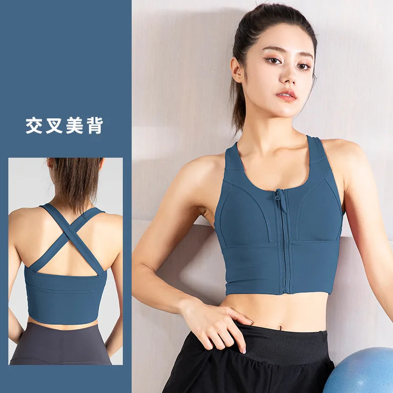 Người phụ nữ mặc áo thể thao xanh, có khóa kéo, dây chéo sau lưng, cầm bóng xanh.