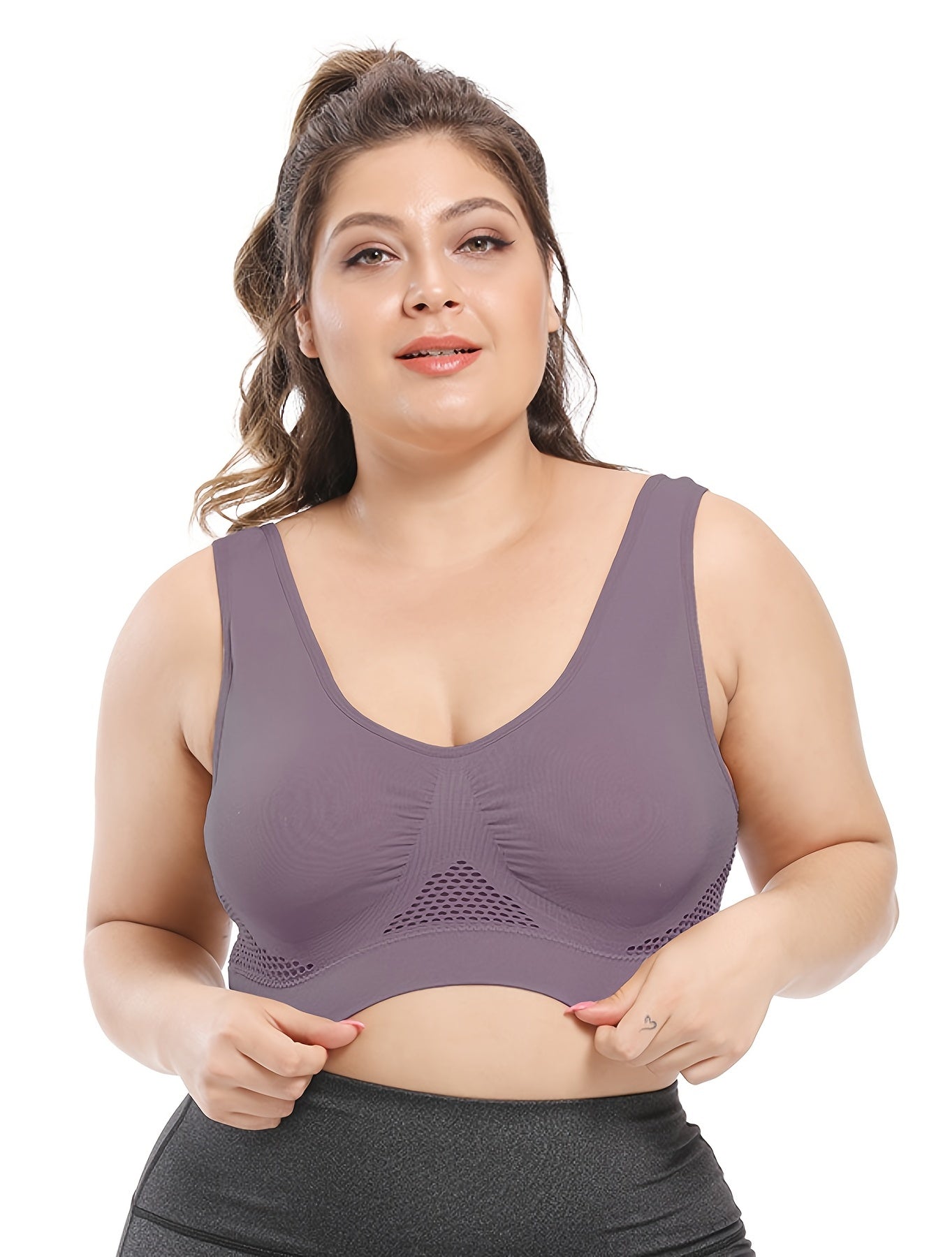Người phụ nữ mặc áo bralette màu tím nhạt, tóc buộc cao, nền trắng.