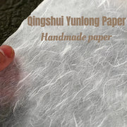 Giấy thủ công màu trắng, mỏng, với vân sợi nổi bật và ngón tay cầm cạnh giấy.
