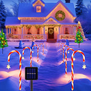 Nhà tuyết trắng trang trí đèn vàng, gậy kẹo phát sáng, cây thông Noel rực rỡ trước sân.