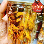 Hũ cá khô vàng óng ánh trong suốt, cầm tay, nắp nhựa. Hình ảnh có logo và số điện thoại bên phải.