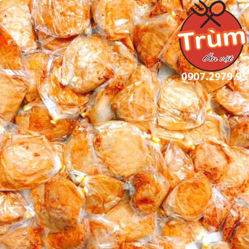 Nhiều viên chả cá chiên vàng ươm bọc trong túi nhựa, logo "Trùm Ăn Vặt" góc phải.