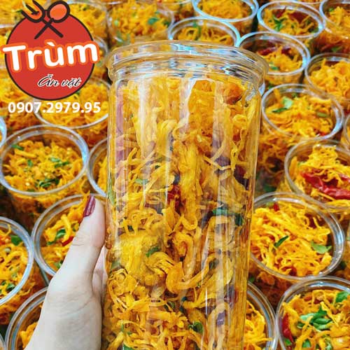 Cốc đầy khô gà xé sợi màu vàng cam, xung quanh là nhiều cốc tương tự.