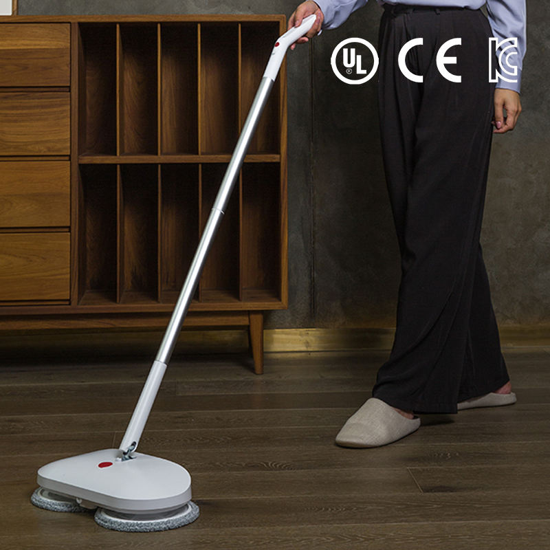 Người sử dụng cây lau nhà điện màu trắng trên sàn gỗ, cạnh kệ gỗ, logos chứng nhận phía trên.