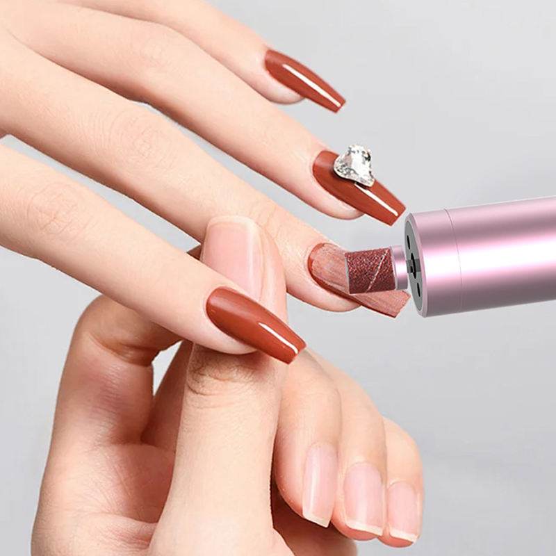 Người đang giũa móng tay dài màu nâu, có đính đá, bằng dụng cụ màu hồng.