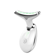 Thiết bị mát xa mặt màu trắng, có đèn LED xanh, hình chữ T, nút nguồn phía trước.