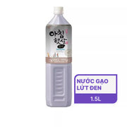 Chai nước màu tím nhạt, nhãn màu trắng có chữ Hàn Quốc, ghi “Nước gạo lứt đen 1.5L”.