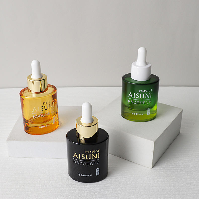 Ba lọ serum màu cam, xanh lá, và đen với nắp ống nhỏ giọt trên nền trắng.
