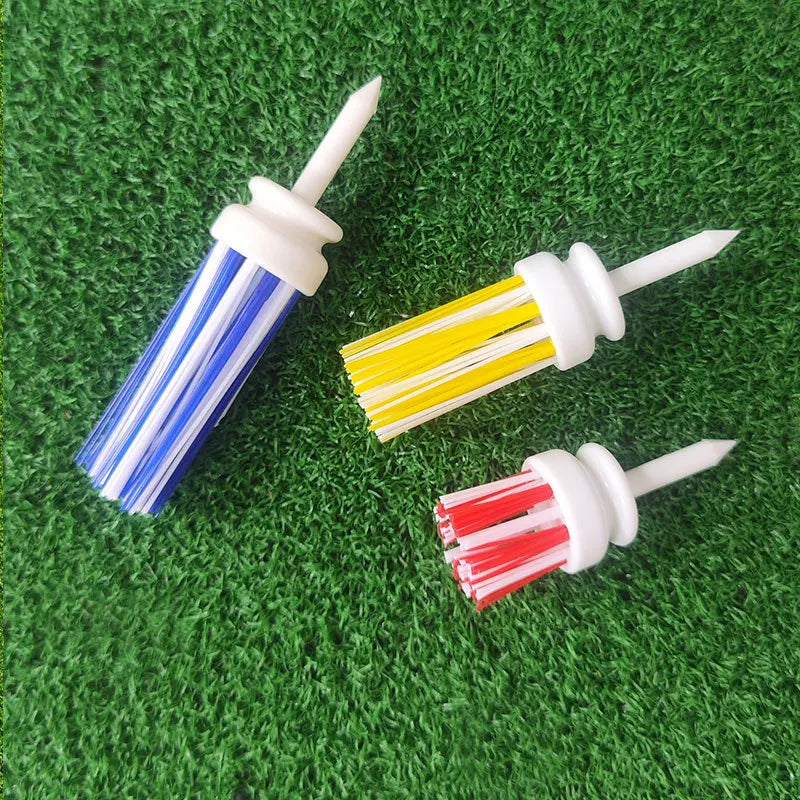 Ba chổi nhựa có lông xanh, vàng, đỏ đặt trên nền cỏ xanh.