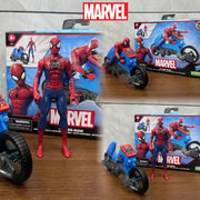 Hình Spider-Man đồ chơi đứng cạnh xe mô tô xanh, hộp nền có logo Marvel.
