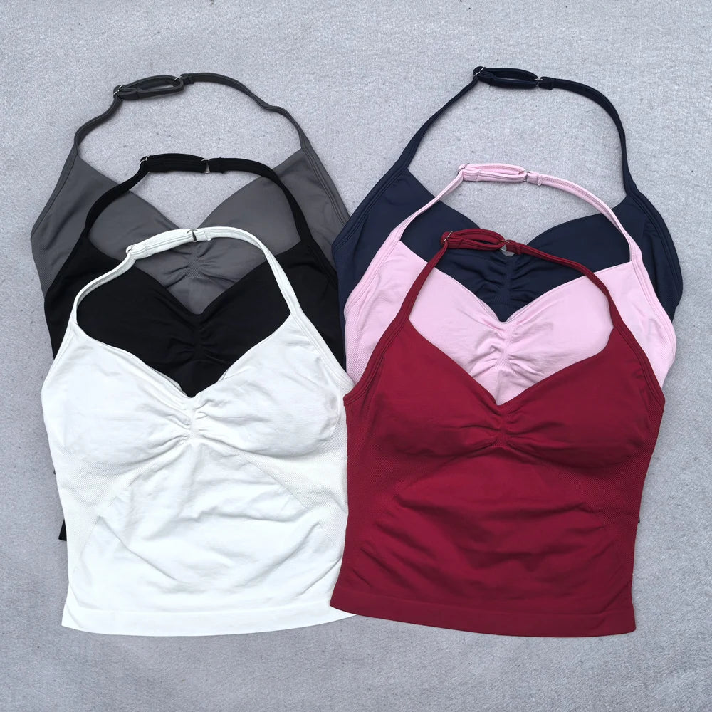 Sáu áo tank top xếp chồng, màu trắng, đen, xám, xanh, hồng và đỏ, trên nền xám.