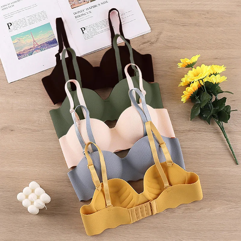 Bốn áo ngực màu sắc khác nhau xếp chồng, có hoa hướng dương và tạp chí gần đó.