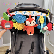 Đồ chơi treo xe đẩy với thú bông màu đỏ, xanh, vàng, xanh dương và họa tiết lá.