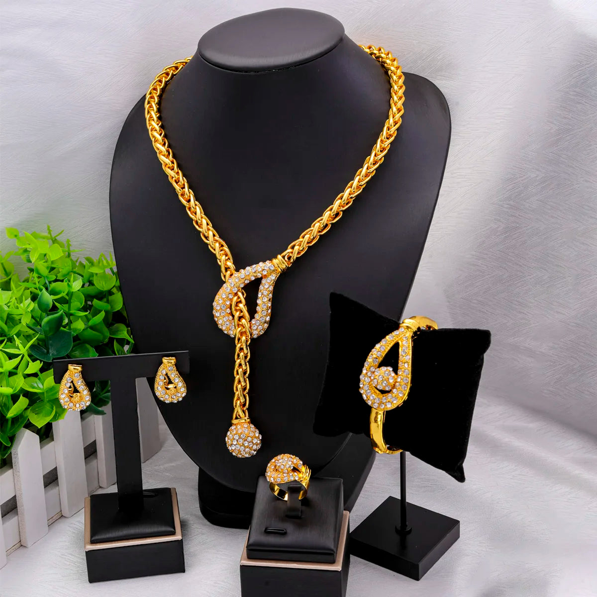 Bộ trang sức vàng đính đá lấp lánh gồm dây chuyền, bông tai, nhẫn và vòng tay trên nền đen.