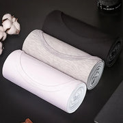 Ba áo thun cuộn tròn màu trắng, xám và đen trên nền đen, cạnh bông gòn trắng.