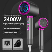 Máy sấy tóc màu đen và hồng, công suất 2400W, có đèn LED xanh và hai đầu phụ kiện.