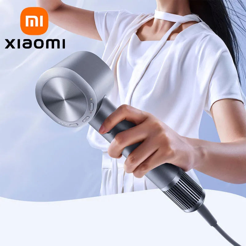 Người cầm máy sấy tóc Xiaomi màu xám, mặc áo trắng, nền xanh nhạt.