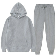 Bộ đồ thể thao màu xám gồm áo hoodie và quần dài, chất liệu nỉ, có túi và dây rút.