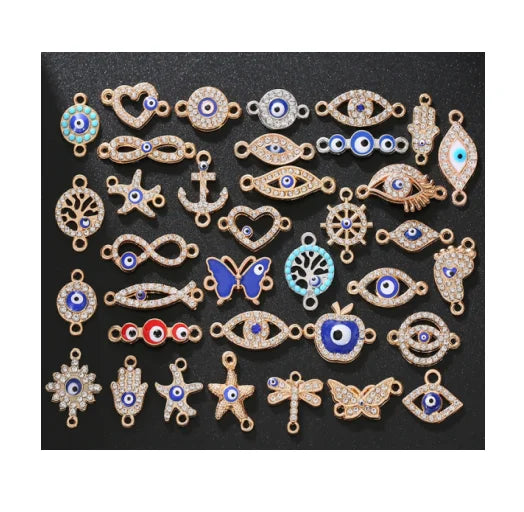Nhiều charm trang sức hình mắt, bướm, ngôi sao, chủ yếu màu xanh dương và vàng trên nền đen.