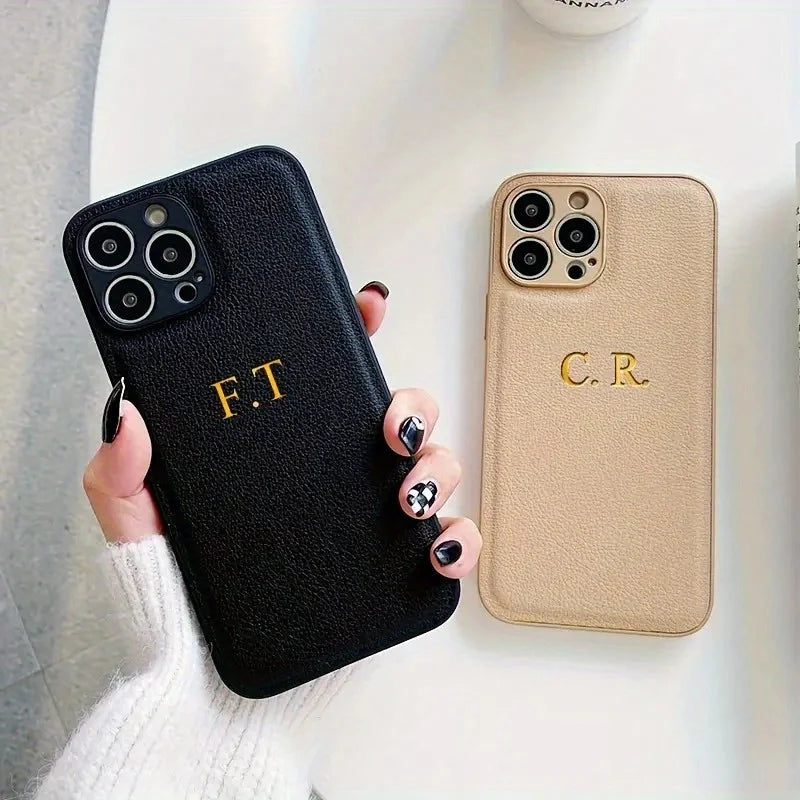Hai ốp lưng điện thoại, một màu đen với chữ F.T, một màu be với chữ C.R, trên nền trắng.