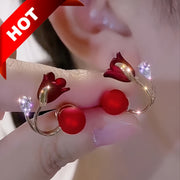 Bông tai hoa đỏ, cánh vàng, đính đá lấp lánh, nền tai người, chữ "HOT" ở góc trái trên.