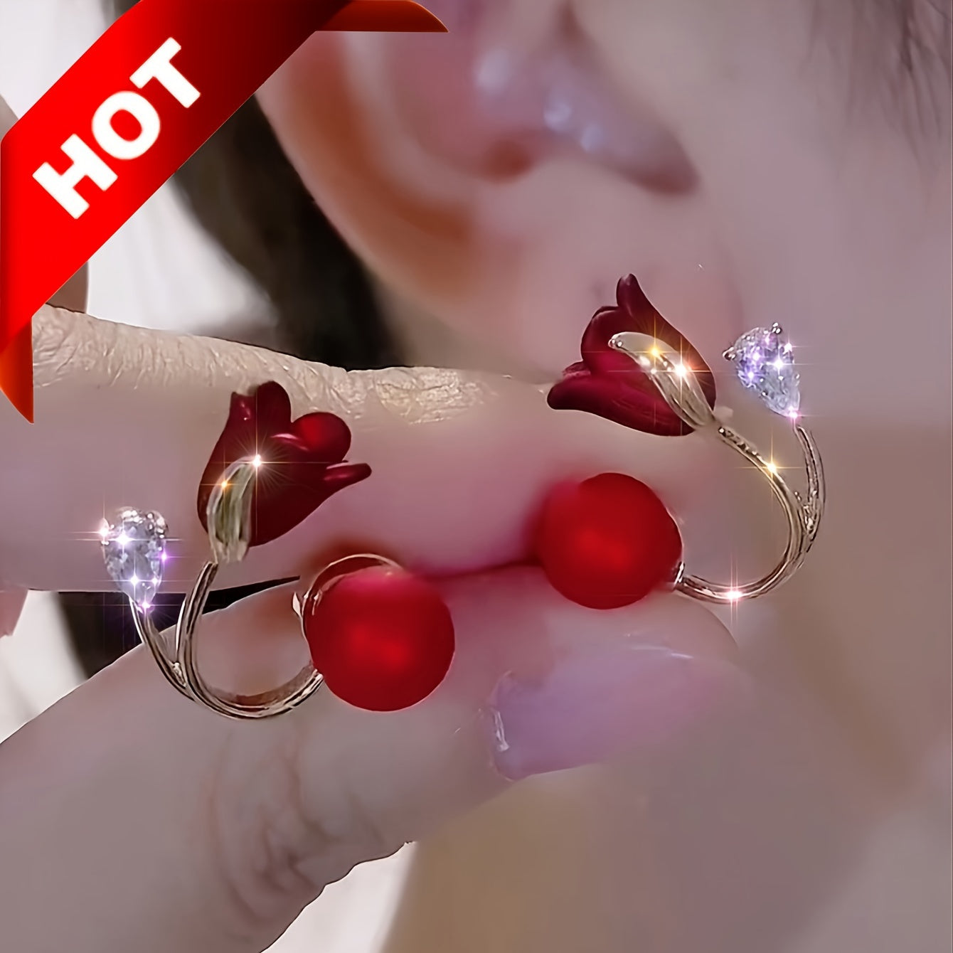 Bông tai hoa đỏ, cánh vàng, đính đá lấp lánh, nền tai người, chữ "HOT" ở góc trái trên.