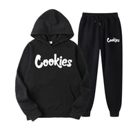 Bộ đồ đen có chữ "Cookies" trắng, gồm áo hoodie và quần dài, kiểu dáng thể thao.