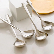 Bốn muỗng inox sáng bóng đặt trên nền trắng, gần khối vuông màu trắng và đĩa tròn màu vàng nhạt.