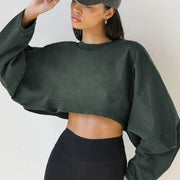 Người phụ nữ mặc áo crop top xanh đậm, quần đen, đội mũ xám, nền trắng.