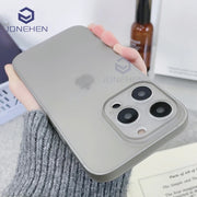 Điện thoại màu xám nhạt trong ốp lưng nhám, ba camera, cầm trên tay người mặc áo len xám.